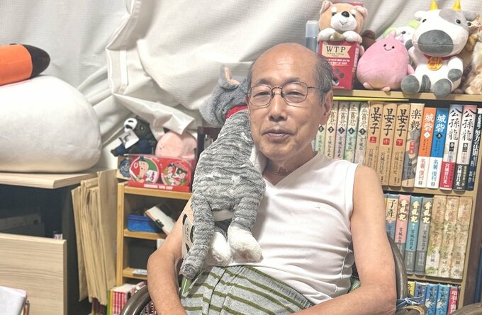 自宅でくつろぎながら、話をする桐谷さん。抱いているのは、日本テレビ「月曜から夜ふかし」出演の際にもらった、“抱きぐるみ”の猫。取材中はずっと傍らに。（写真＝ダイヤモンドZAi編集部）