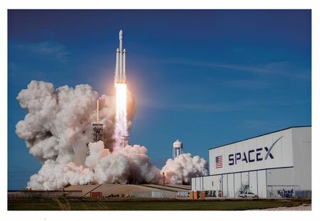 宇宙ロケットが発射している写真。発射台の傍にはスペースX社のロケット組立・格納庫がある。